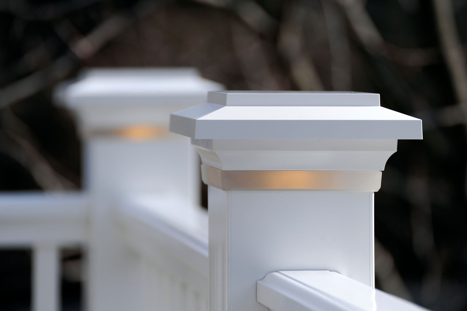 White wooden fence posts with small warm lights along a walkway outdoors