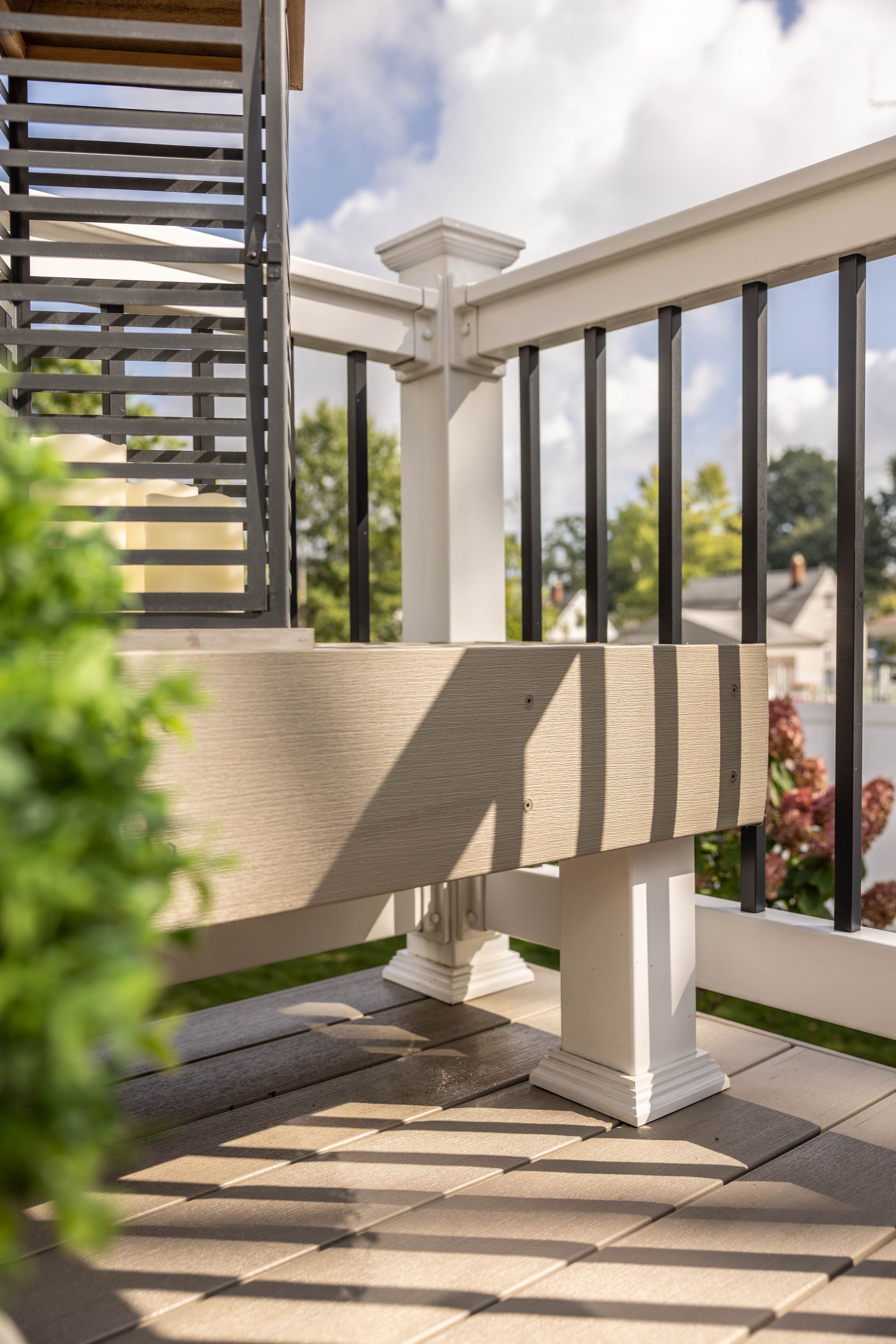 Outdoor patio with a stone table, white railing, and sunlight casting shadows on the floor