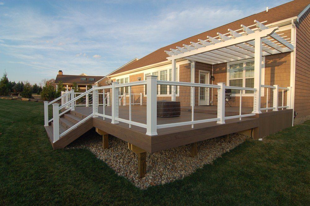 Back porch deck with white railing and stairs on a tan house at sunset