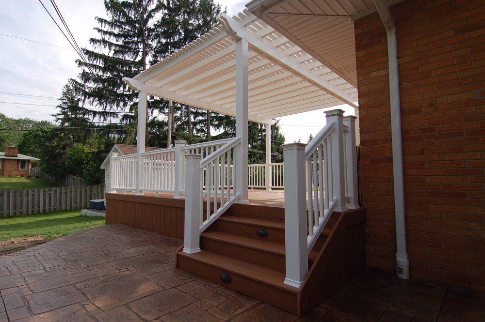 Covered wooden front porch with white railings and steps beside a brick house