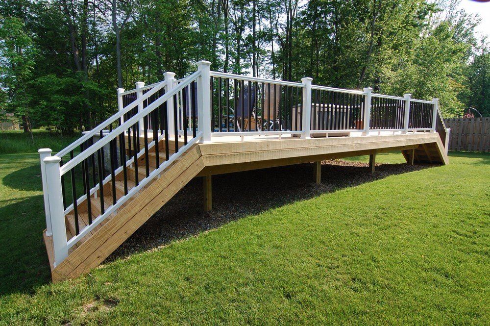 White wooden accessibility ramp with railings on a grassy yard, leading to a raised deck outdoors