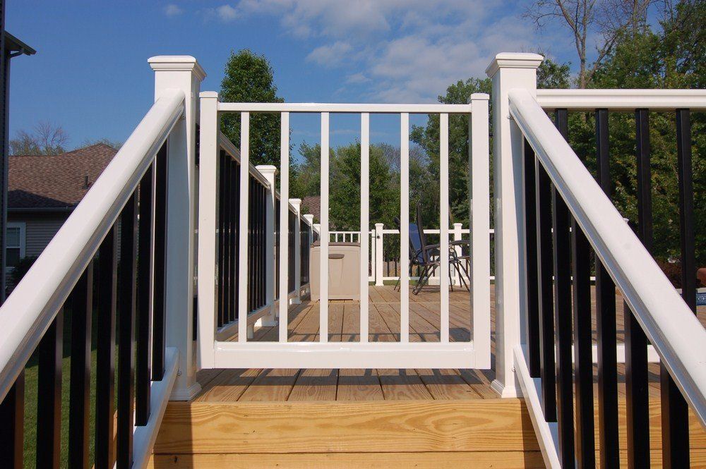 White wooden deck stairs and railing leading down to a backyard under a blue sky