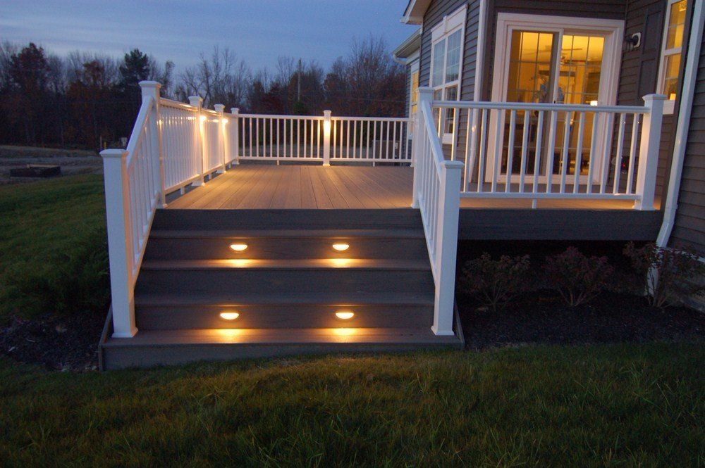 Lit porch steps with white railings and glowing deck lights at dusk