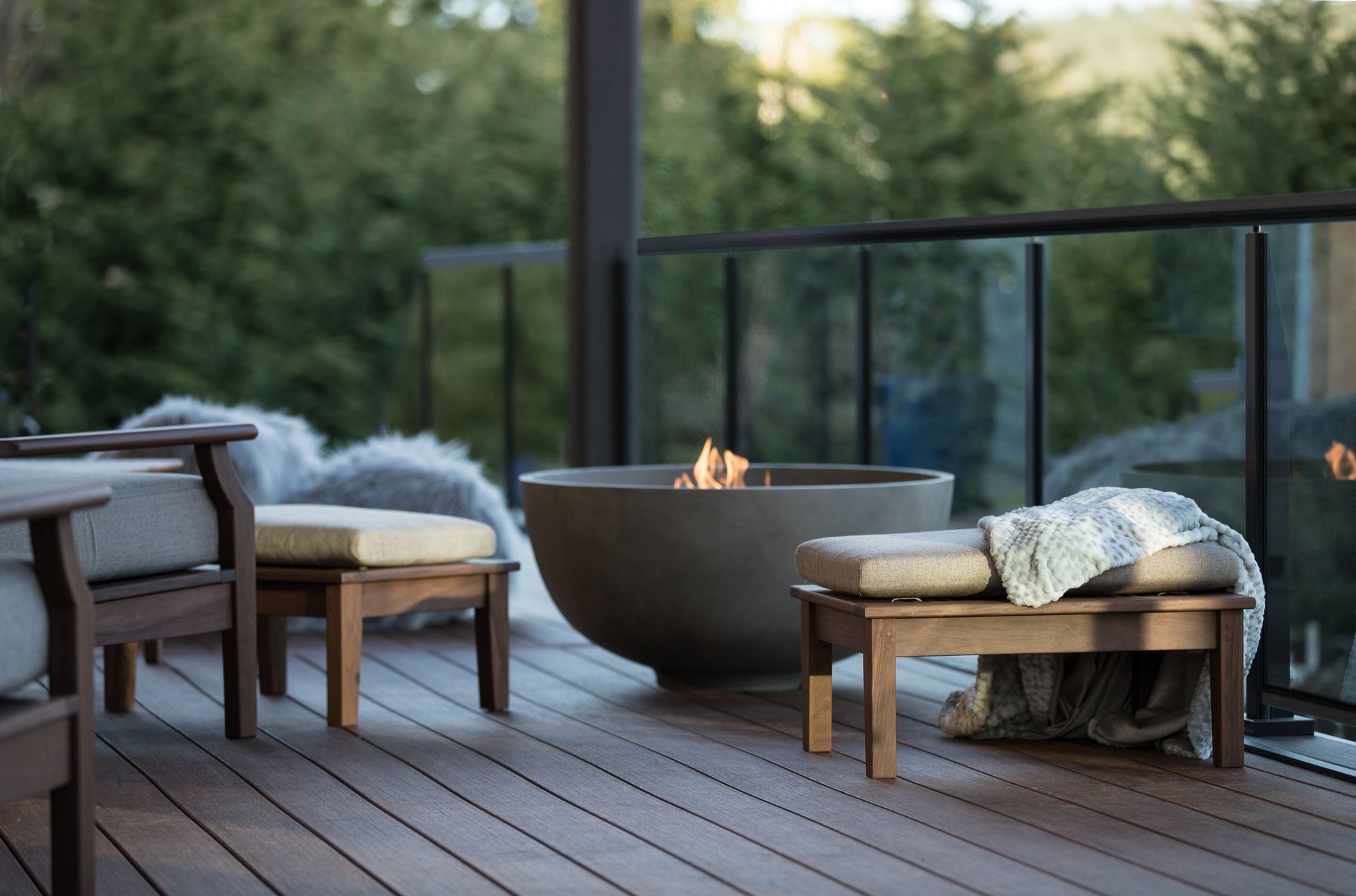 Modern patio seating around a small fire bowl on a wooden deck at dusk