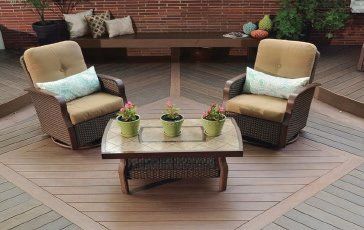 Outdoor patio seating area with two cushioned chairs and a coffee table on a wooden deck.