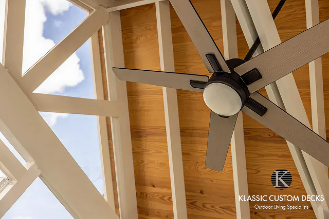 Ceiling fan on a vaulted wood ceiling with white beams and a skylight