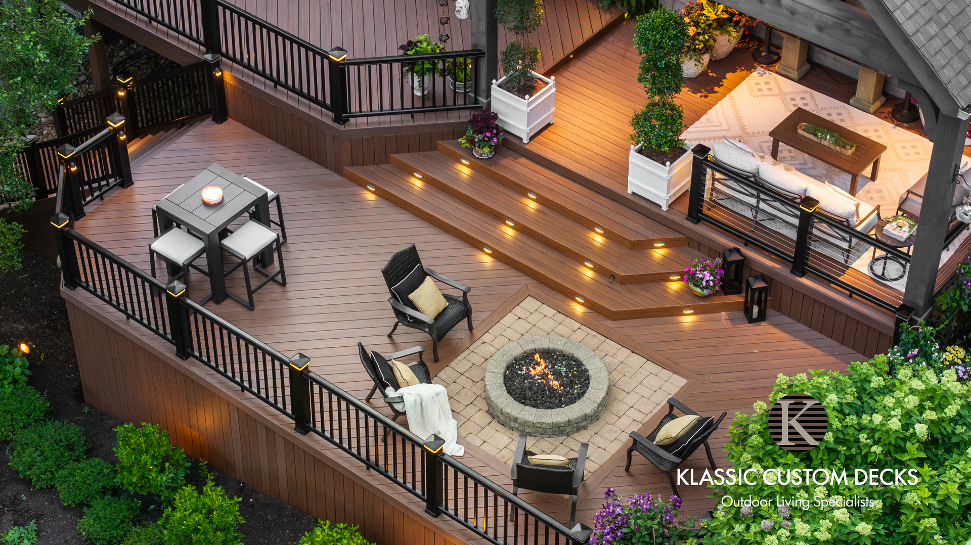 Outdoor deck with string lights, fire pit seating, and dining tables on a wooden patio at dusk