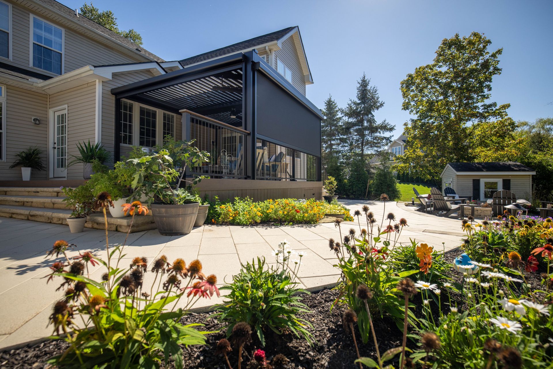 Modern house patio with pergola, flower beds, and sunny landscaped garden
