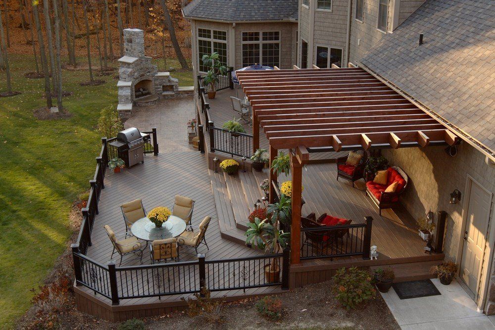 Back patio with outdoor seating, pergola, grill, and potted plants beside a house