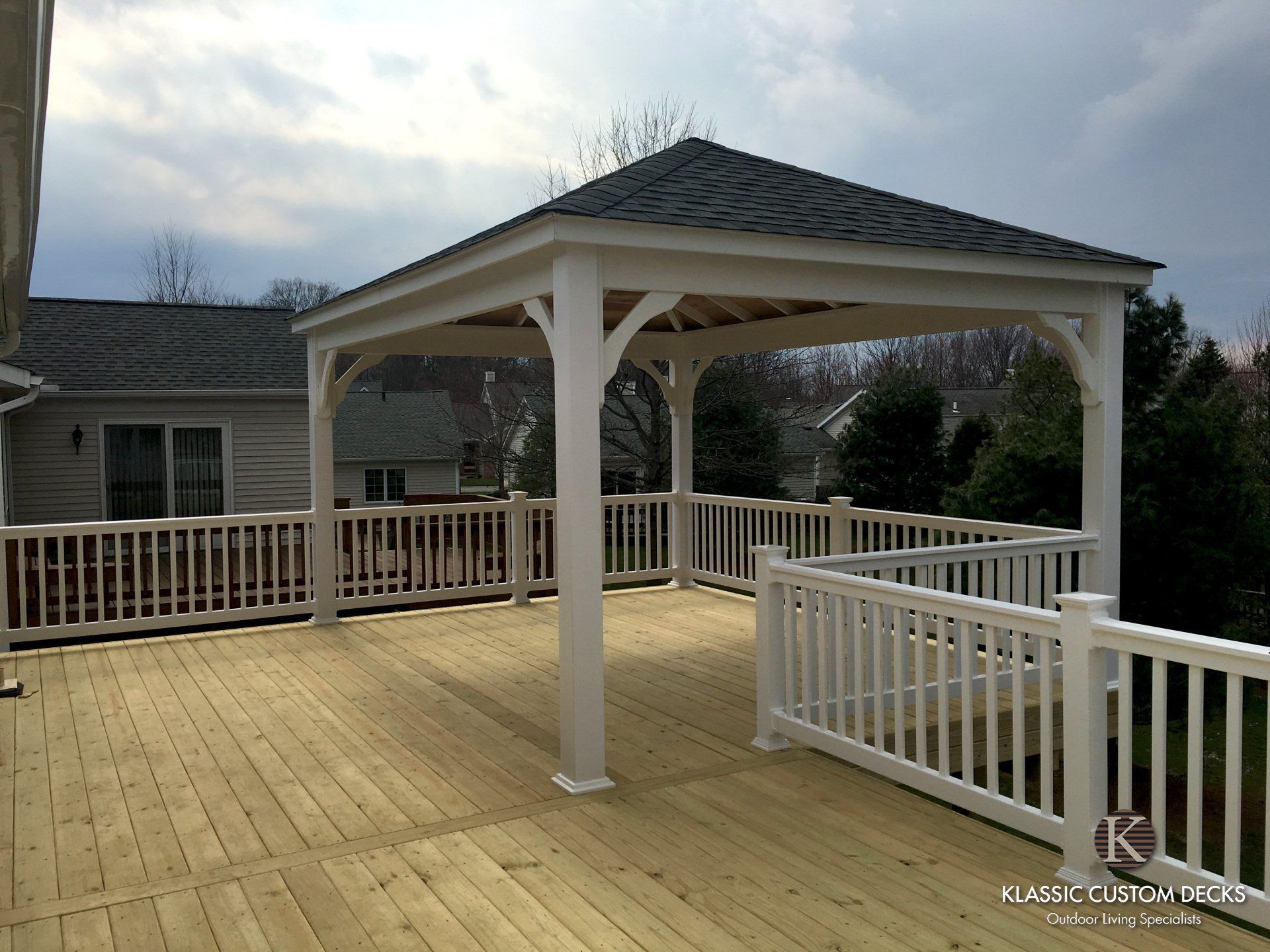 Wooden deck with white railings and a covered gazebo overlooking a yard