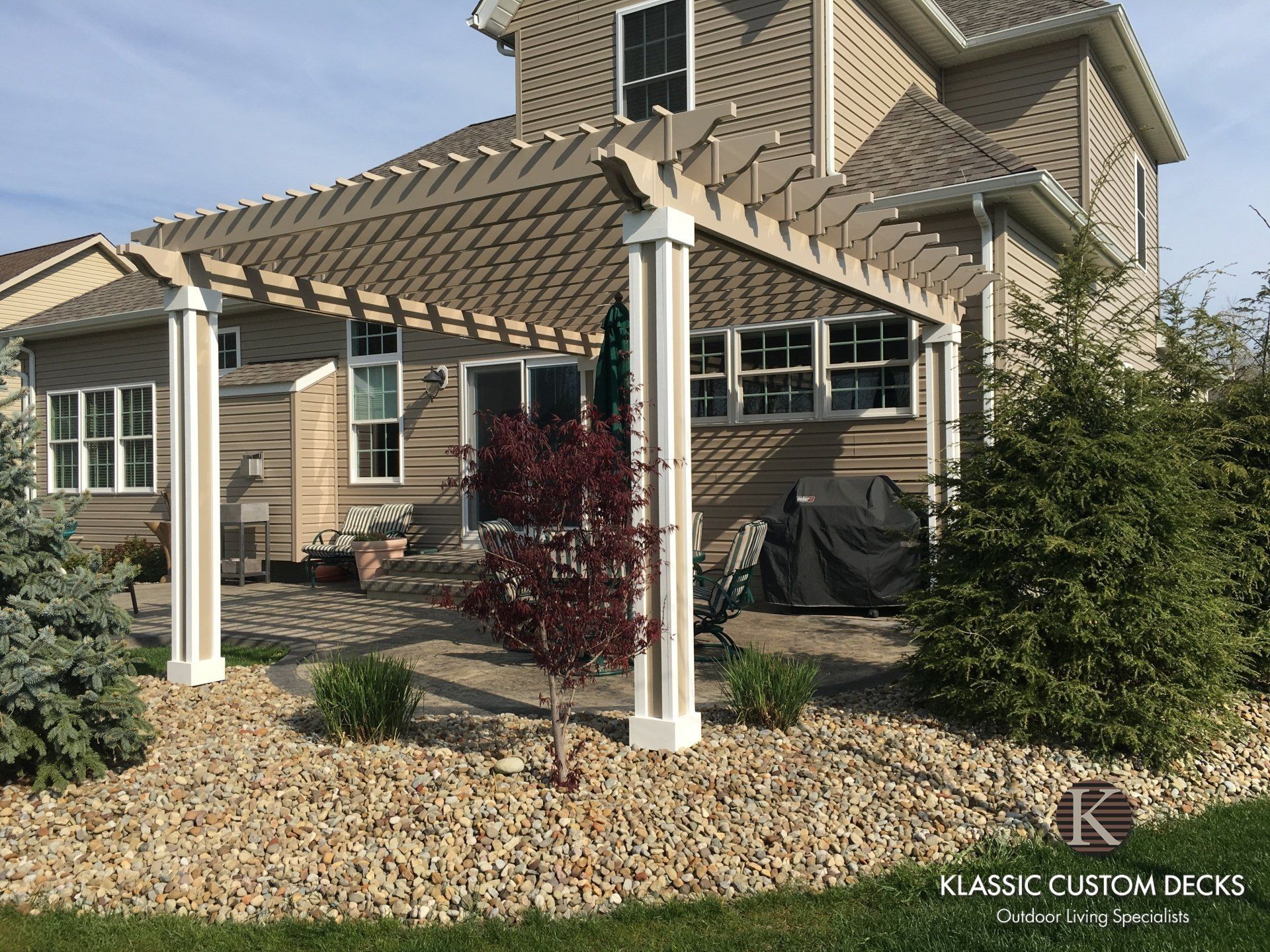 Residential home with a covered patio, white columns, and landscaped gravel and shrubs