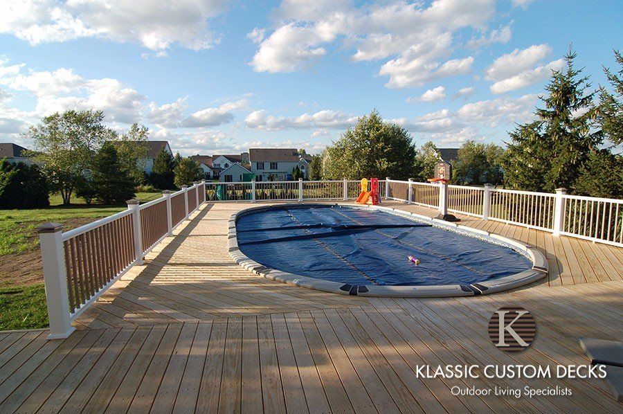 Backyard wooden deck with a covered round pool and white railing under a sunny sky