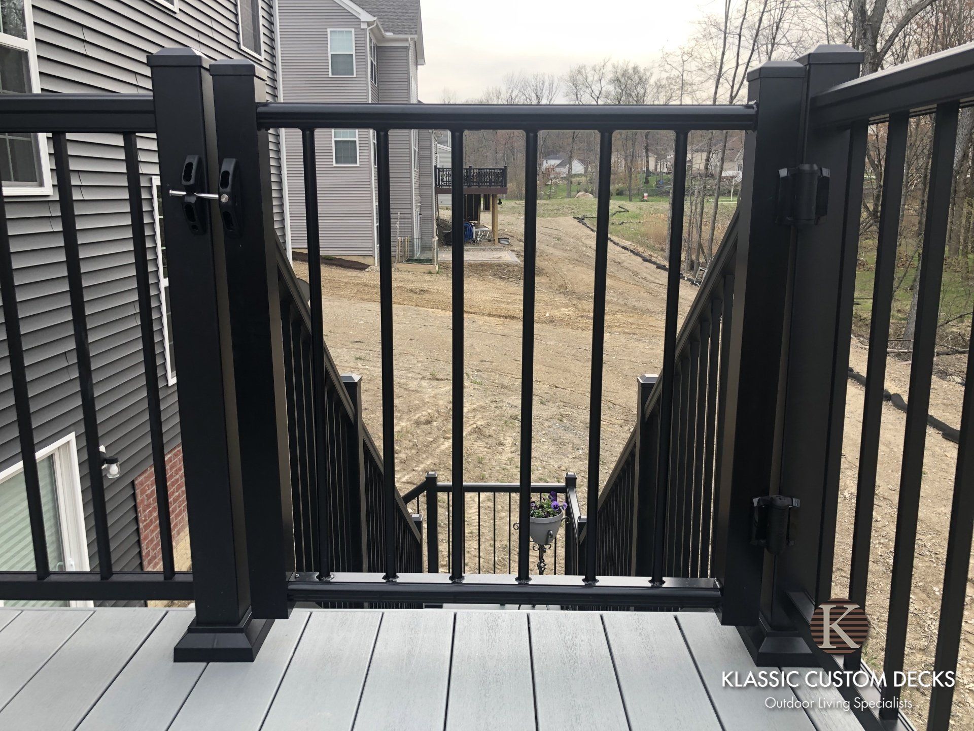 Deck with black railing and gate overlooking a backyard and neighboring houses