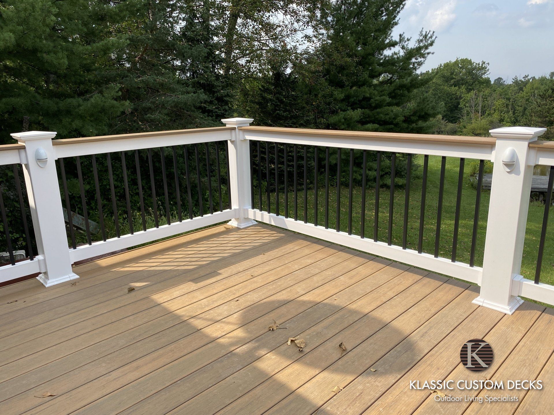 Wooden deck with white railing overlooking a grassy yard and trees