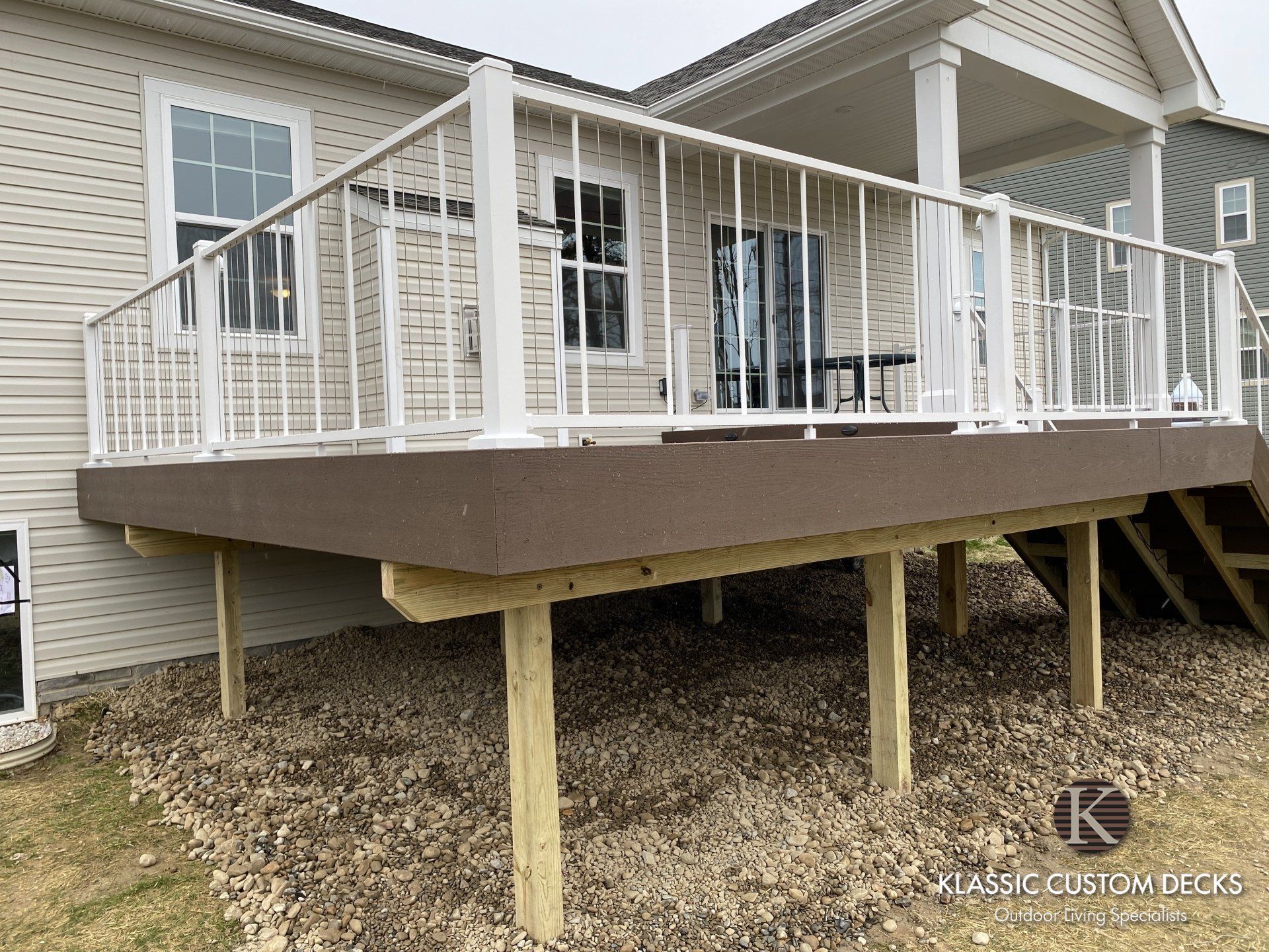 Back porch deck with white railing and tan support posts on a house exterior