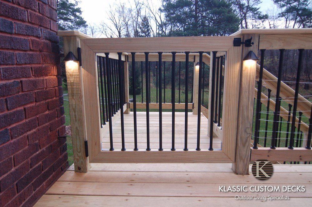 Wood deck with black metal gate and railing at the top of outdoor stairs