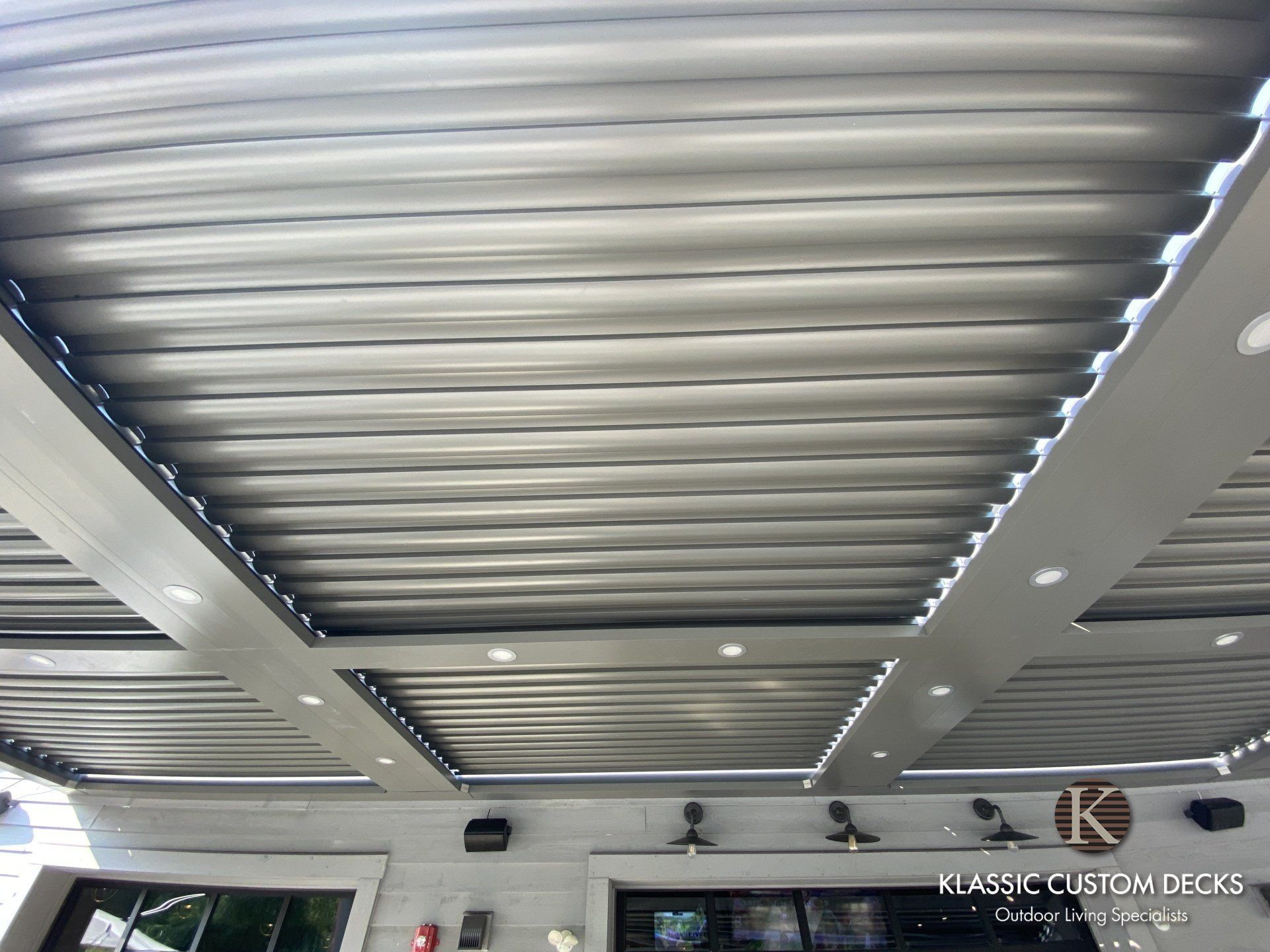 Modern ceiling with curved metallic slats and recessed lights in a sleek indoor public space
