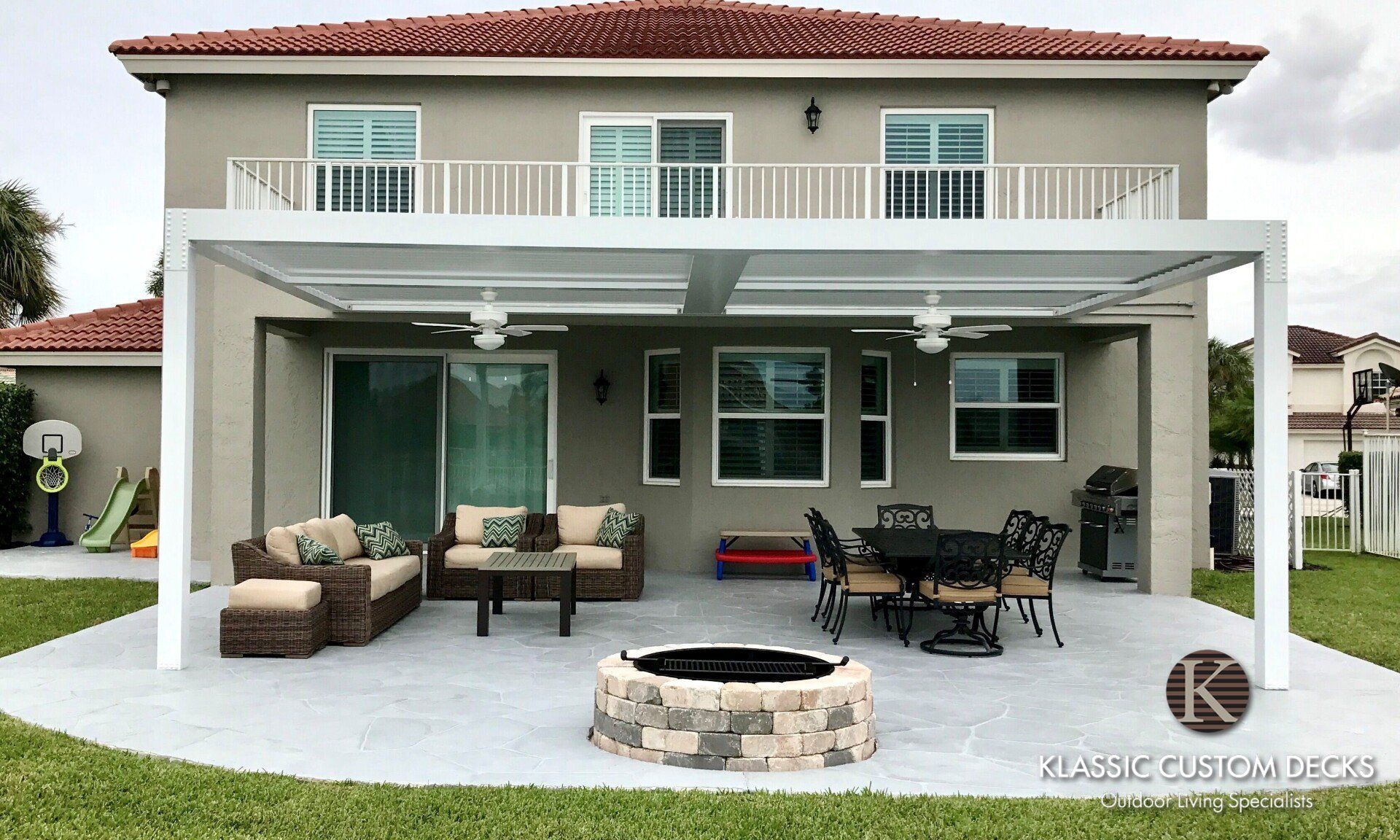 Two-story home with a covered patio, outdoor seating, dining table, and fire pit under a pergola