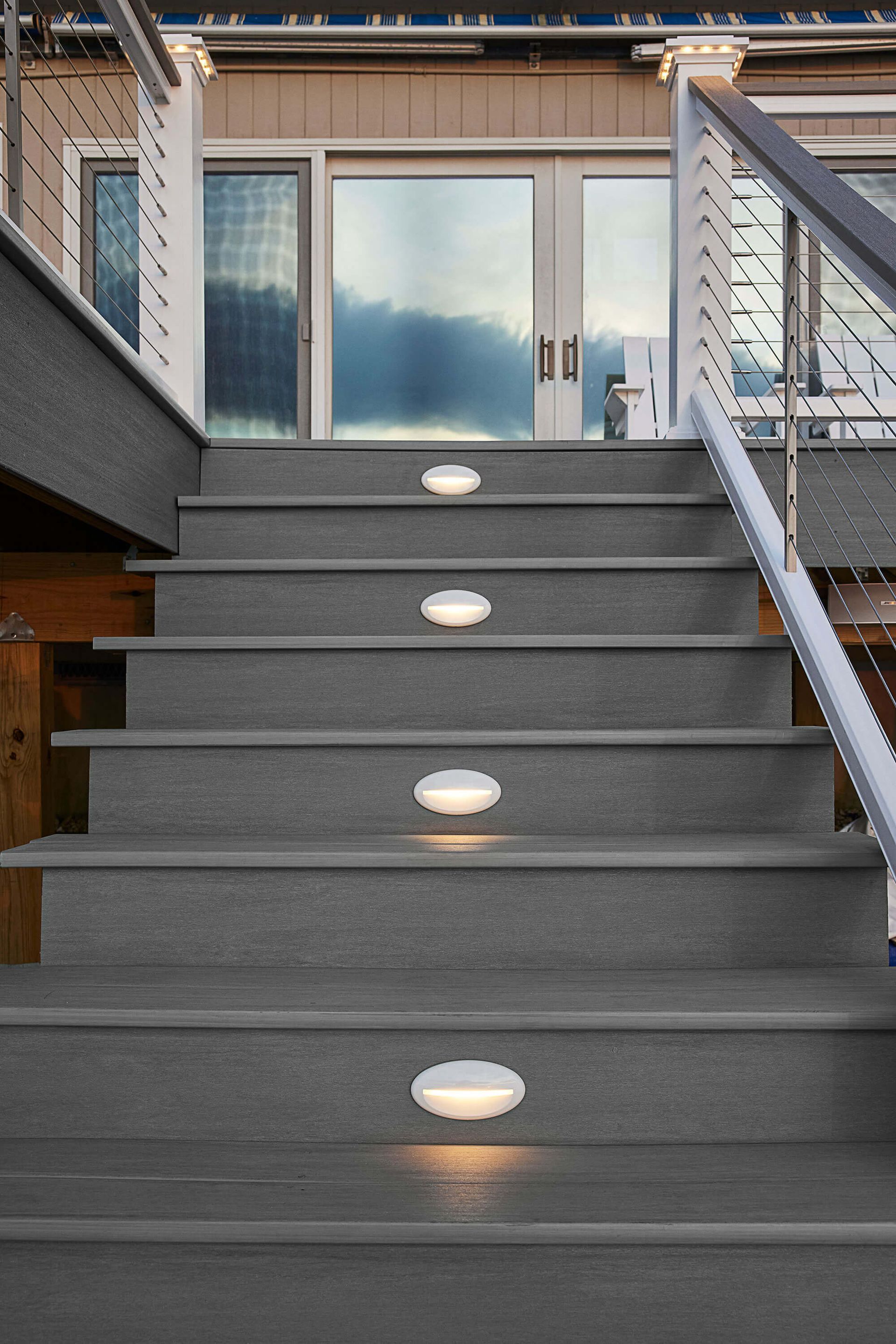 Outdoor stairs with lit step lights leading to a glass door at an apartment entrance