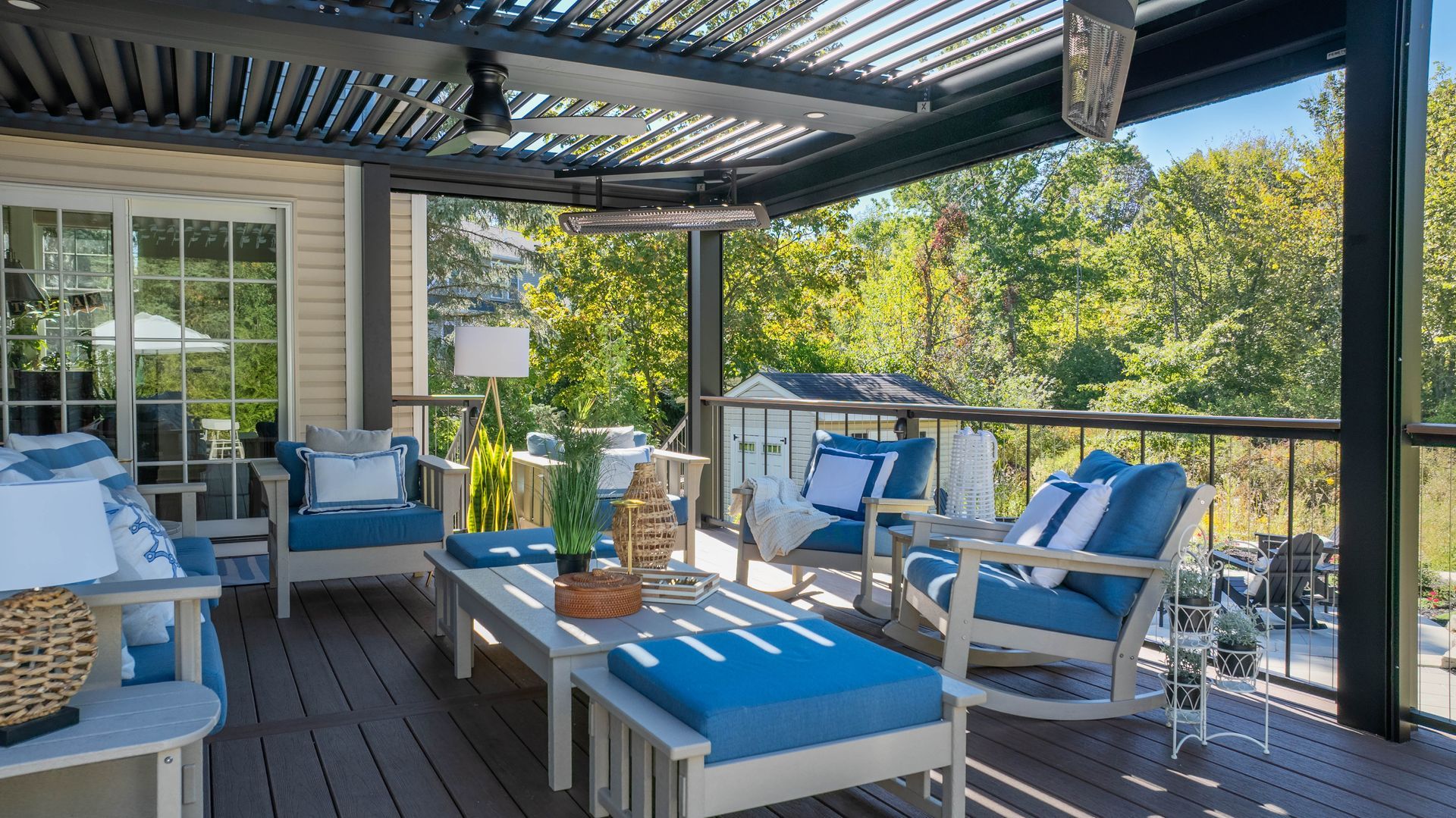 Covered patio with blue-and-white outdoor seating and a central coffee table in a sunny garden.