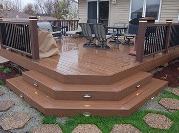 Wooden backyard deck with seating and a short staircase leading down to stepping stones