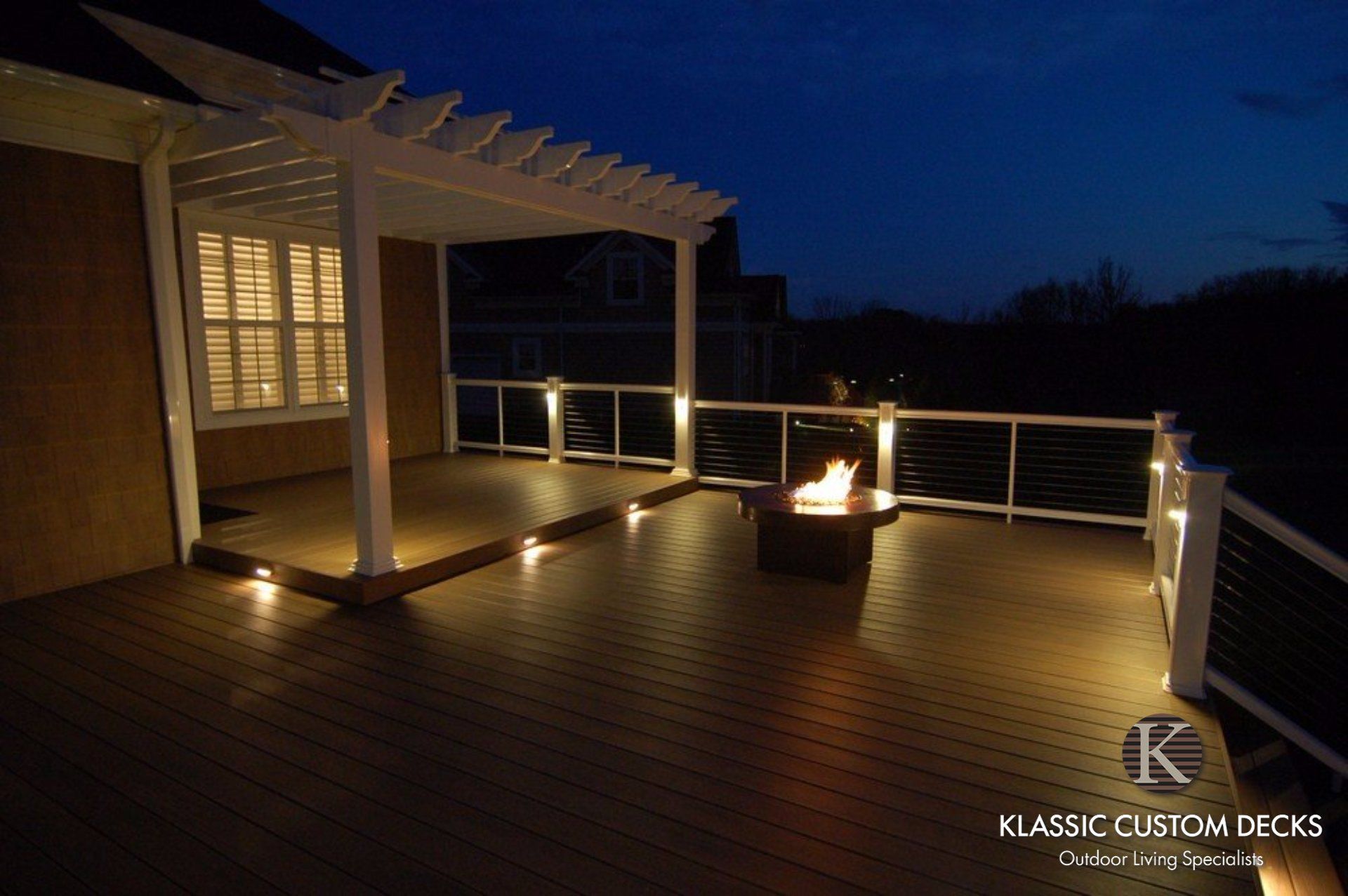 Deck at dusk with warm accent lighting, railing, and ocean view