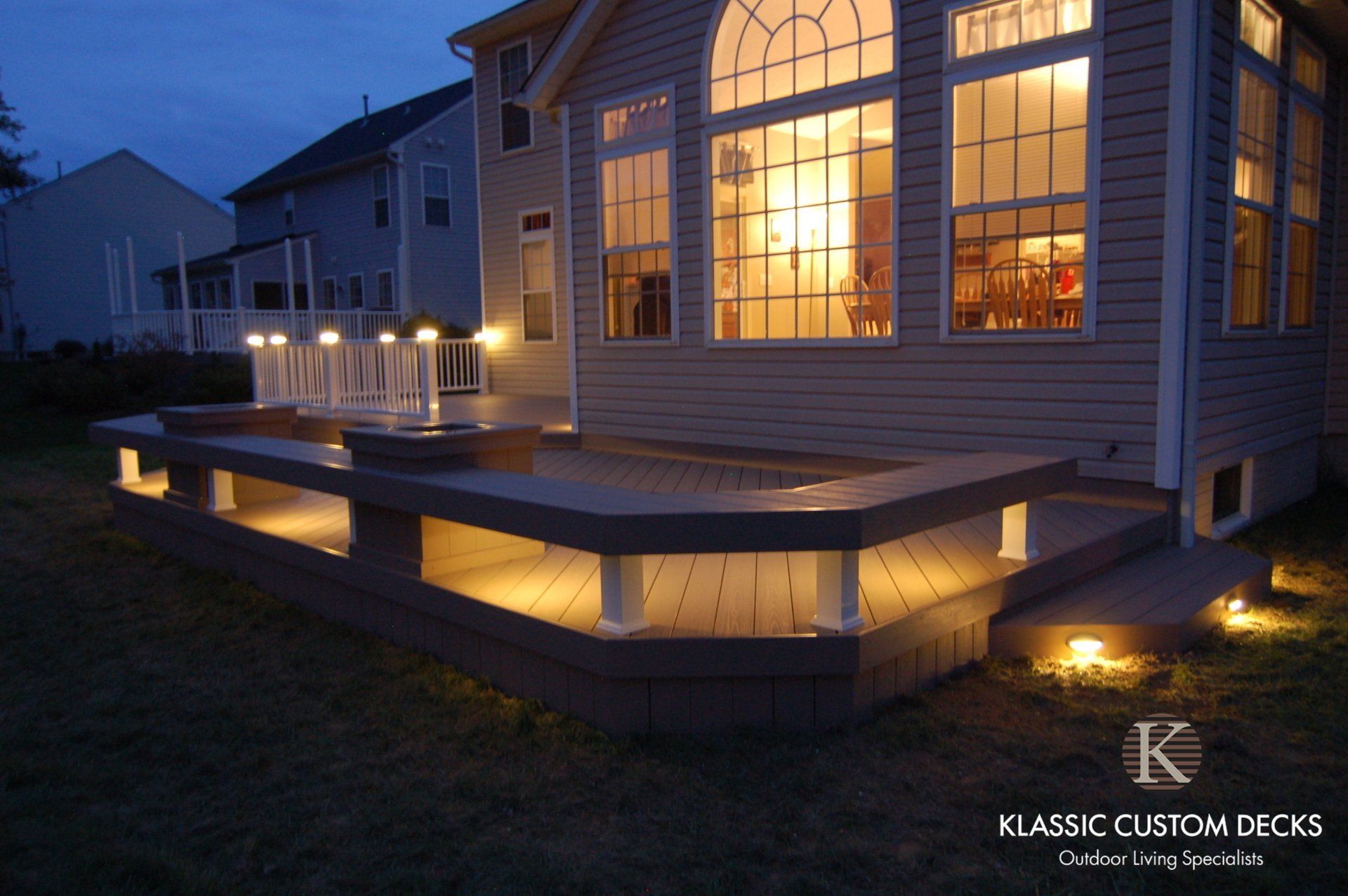 Backlit deck with built-in step lights beside a lit house at dusk