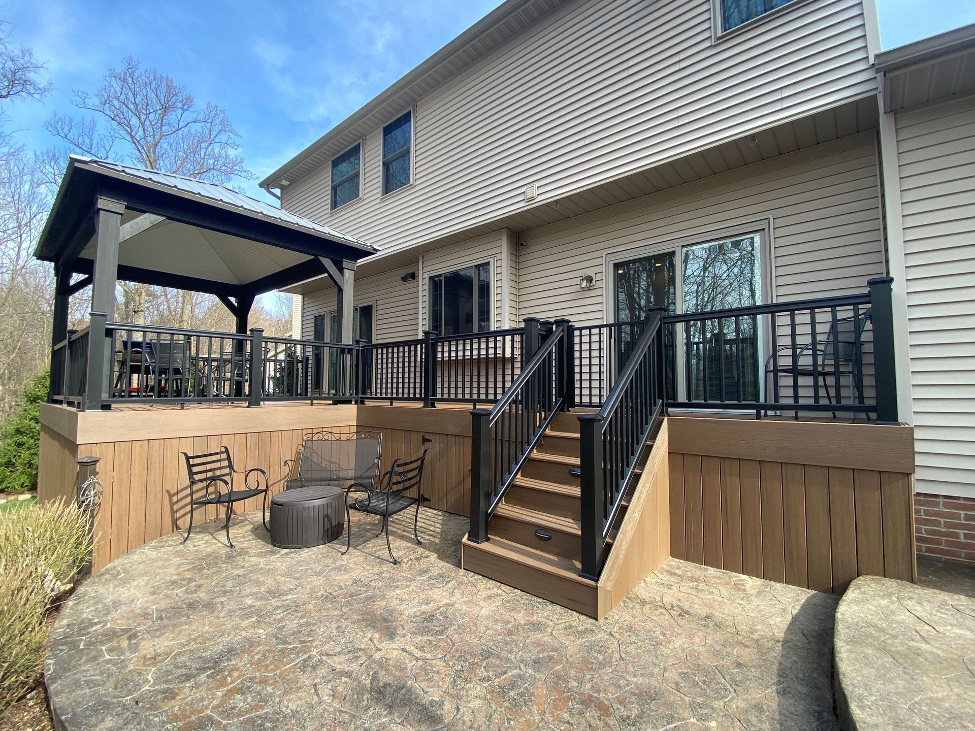 Backyard deck with stairs, black railing, gazebo, and outdoor seating beside a house