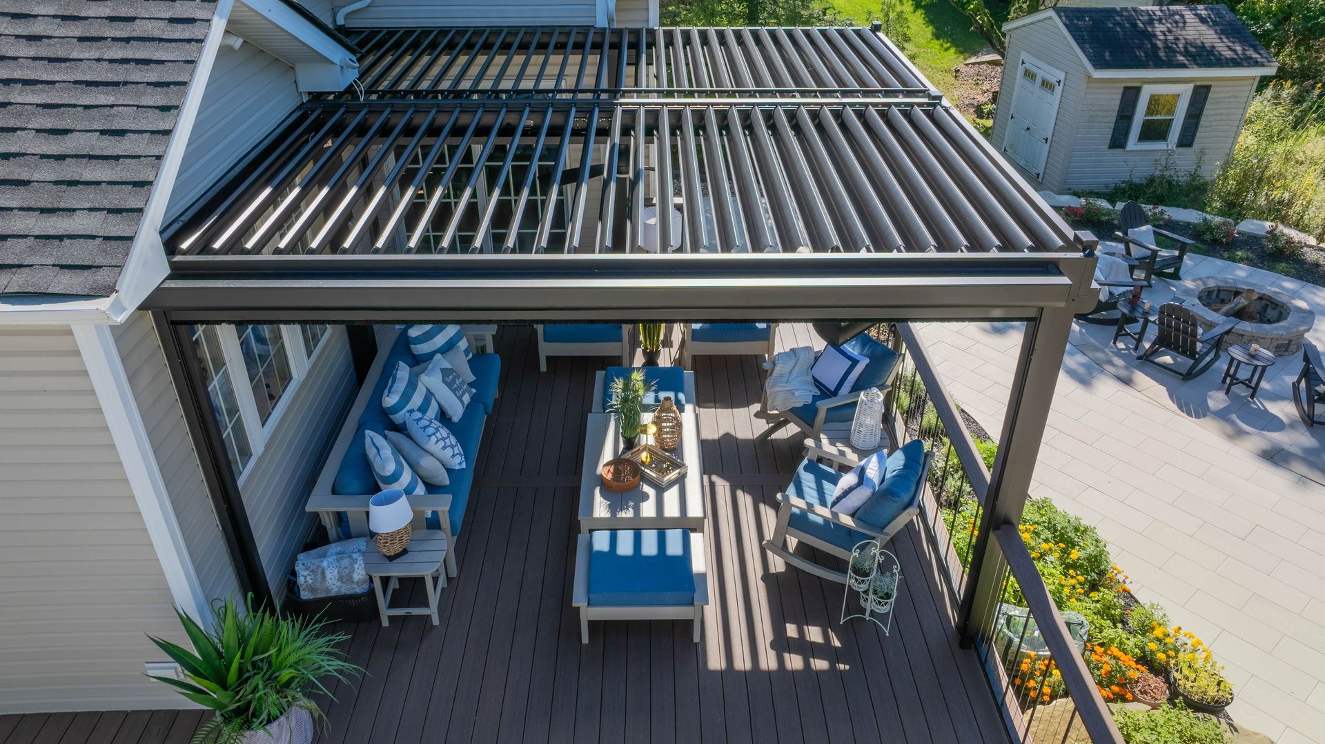 Backyard patio with pergola, striped navy-and-white furniture, and potted plants in bright sunlight