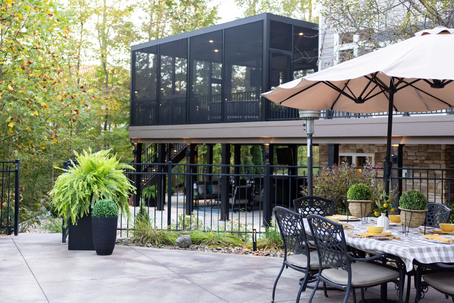 Outdoor patio dining area beside a modern black glass building with tables, chairs, and umbrellas