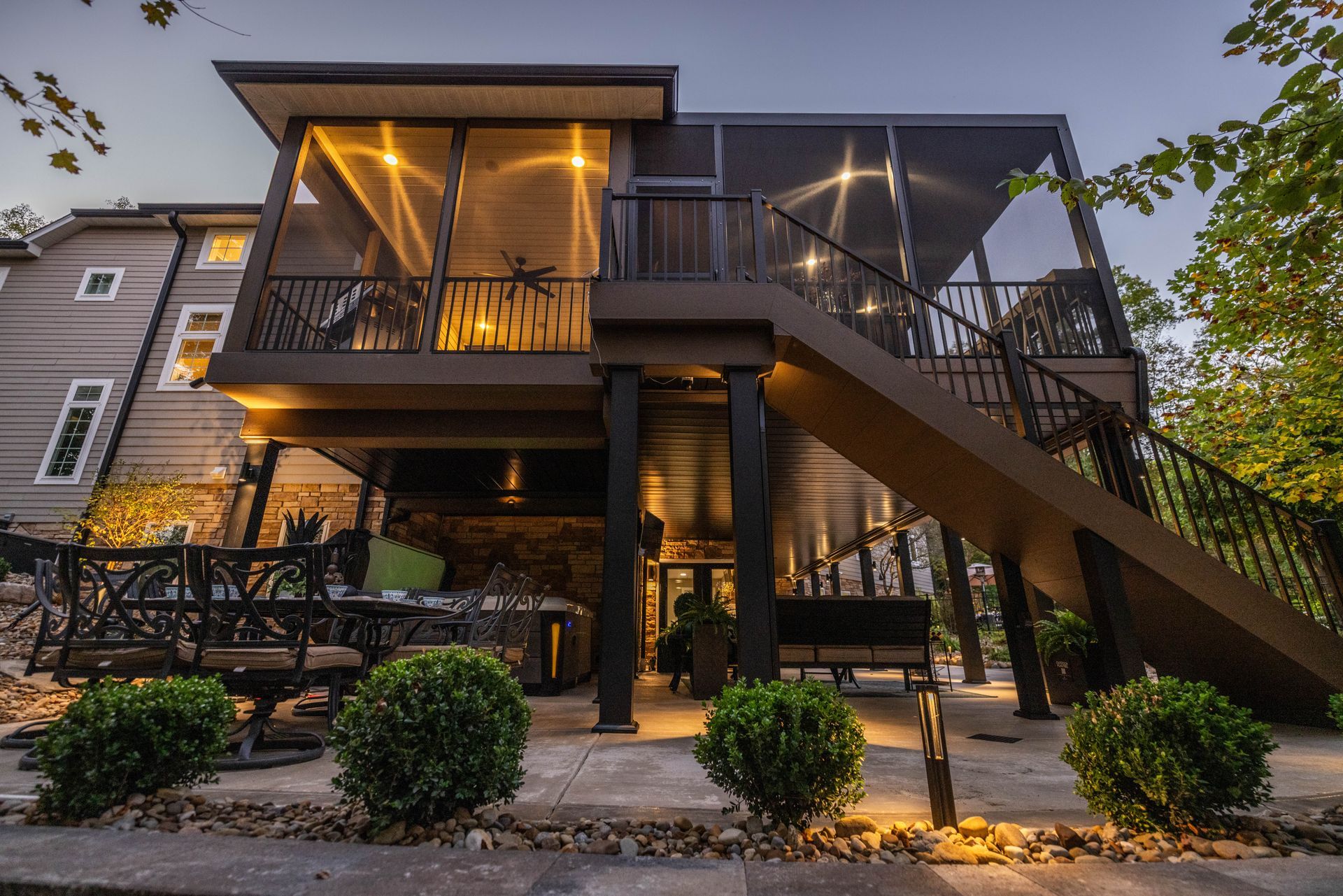 Two-story house with a lit balcony and staircase at dusk