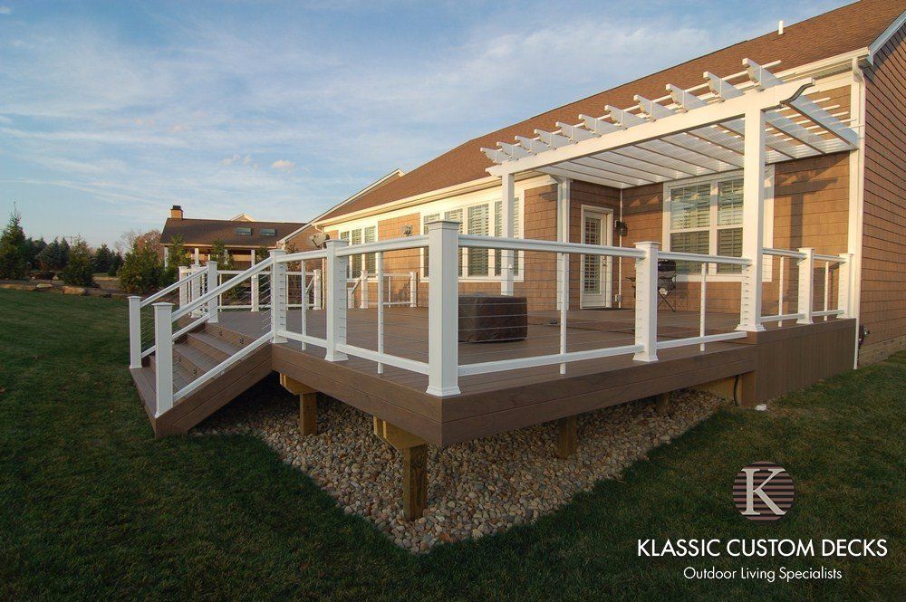 White custom deck with railings and stairs attached to a house at sunset