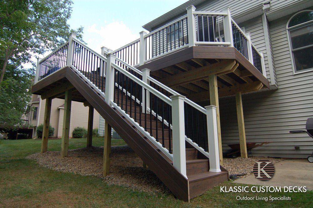 Staircase and elevated deck attached to a house, with white railings and support posts.