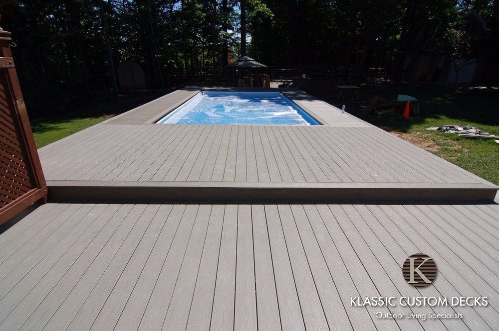 Backyard deck with a rectangular swimming pool in the center, surrounded by tan composite decking.