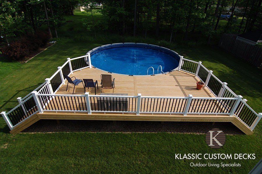 Backyard deck with white railings and blue above-ground pool, furnished with patio chairs and table