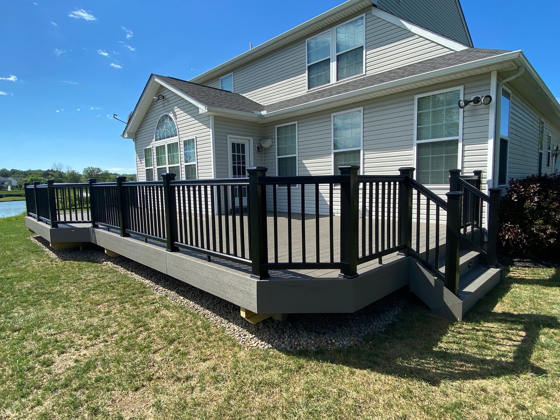 White house with a black-railed wooden deck and ramp on a sunny day