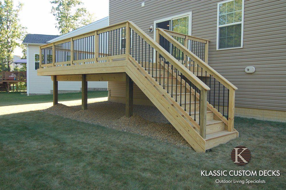 Raised wooden deck with stairs attached to a house in a backyard