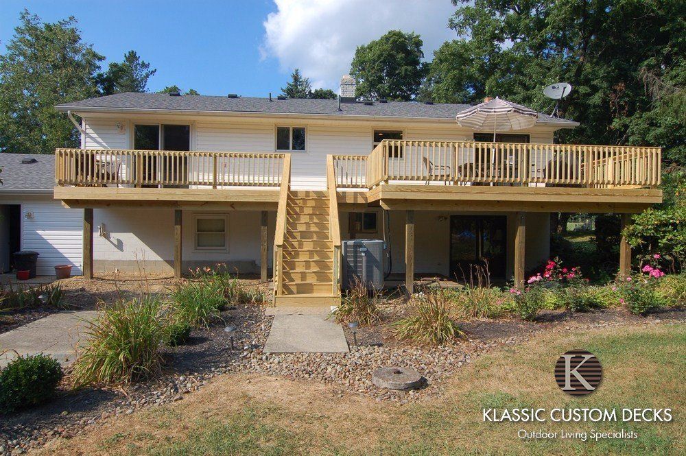 Two-story house with a large wooden deck, central staircase, and landscaped front yard