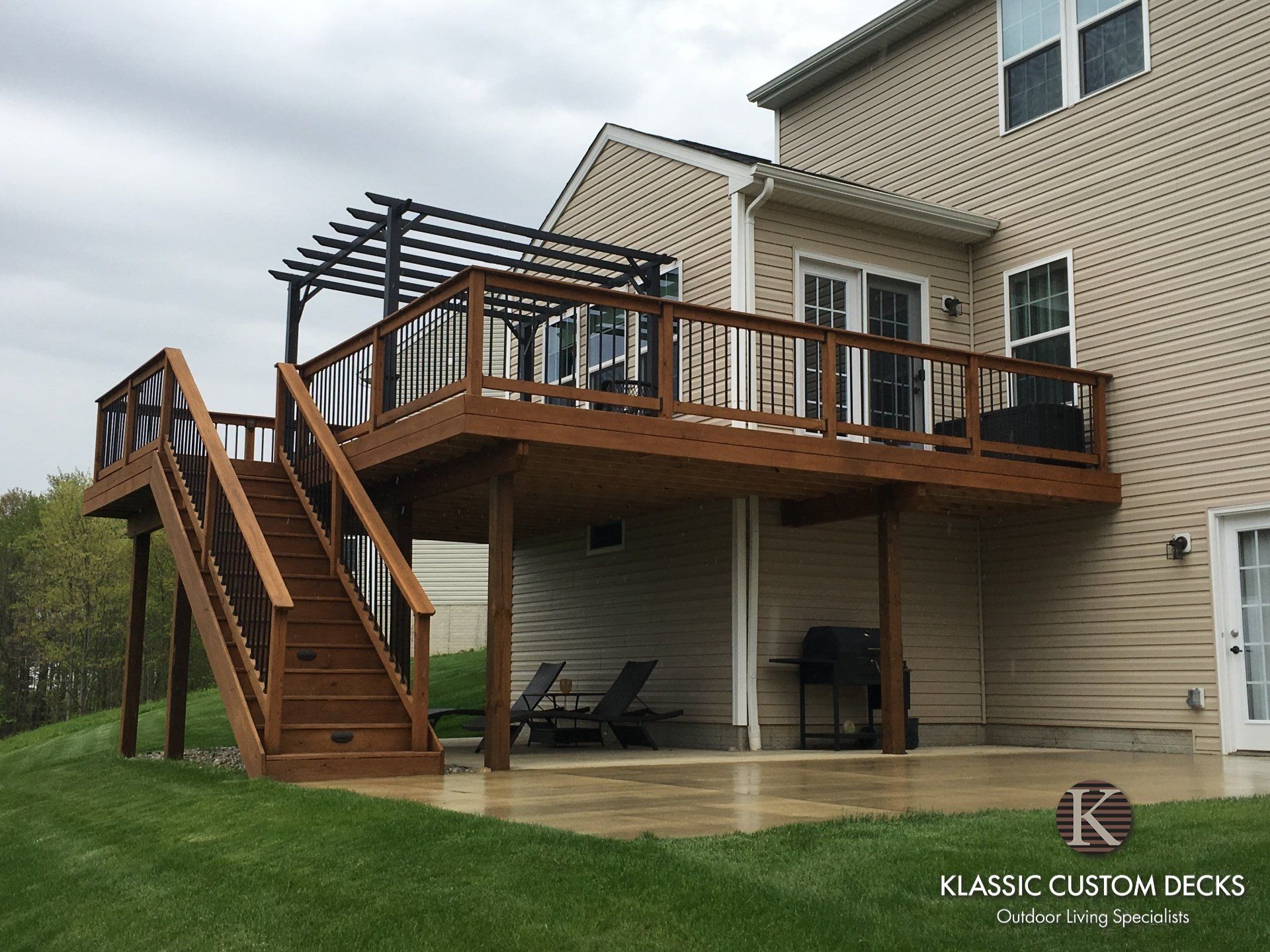 Wooden backyard deck and staircase attached to a beige house with a covered patio below