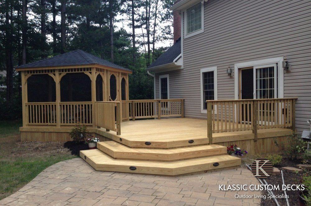 Wood deck with gazebo beside a house, featuring multi-level steps and railings