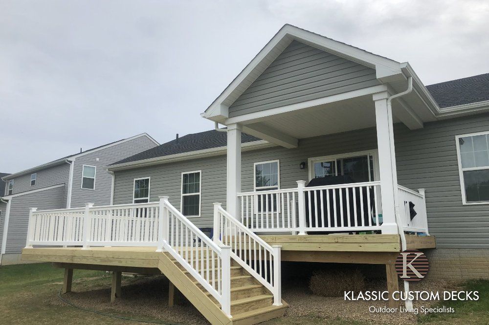 Gray house with white porch, railings, and wheelchair ramp on a cloudy day