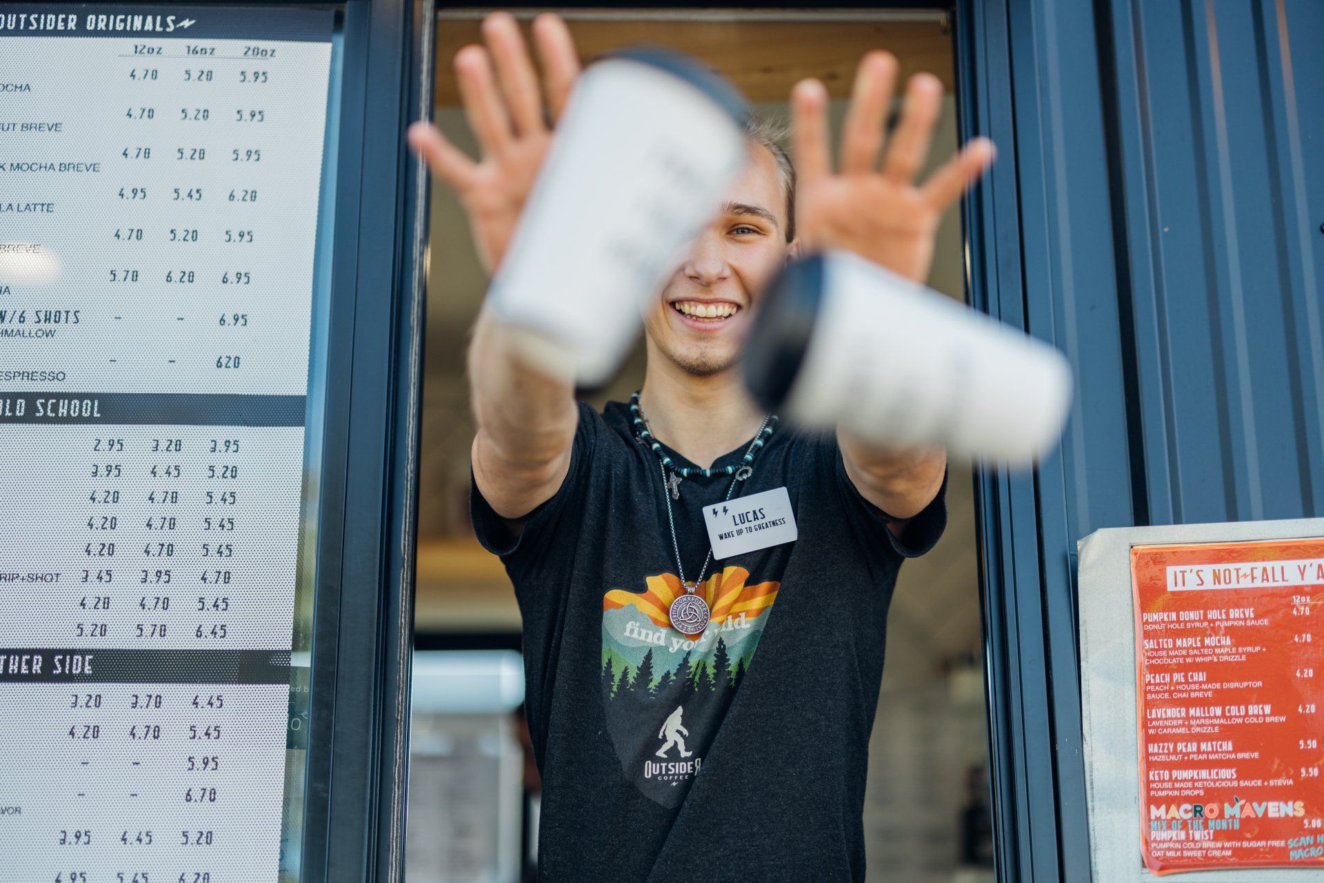 Smiling person juggling white clubs in front of a blue wall and posters