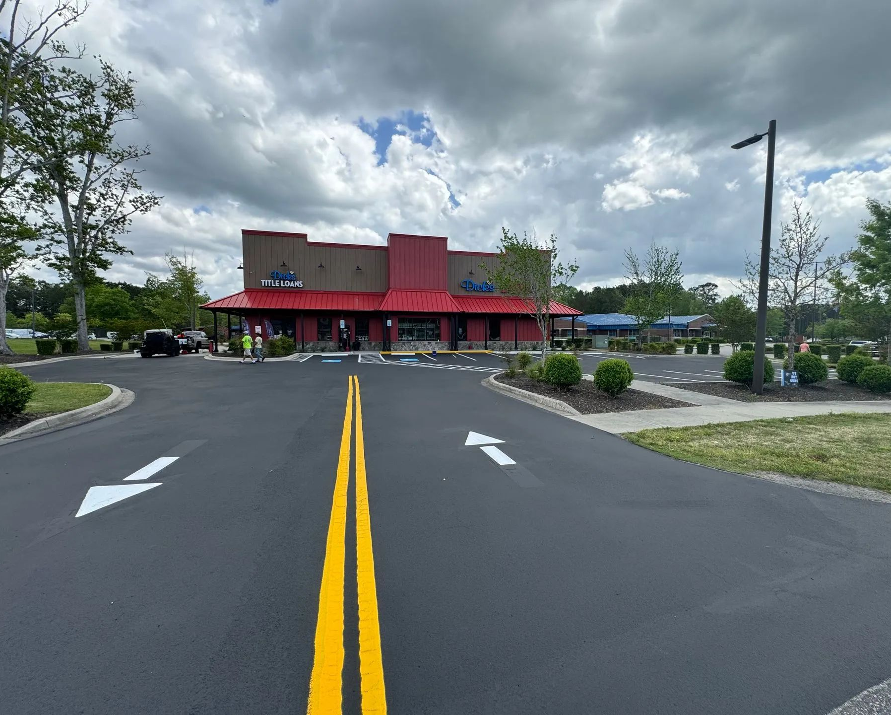 Road leading to a red-roofed restaurant with a covered entrance under cloudy sky.
