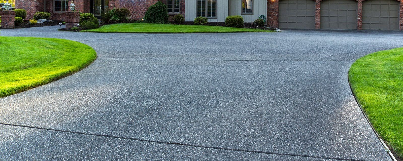 Gravel driveway leading to a suburban house with green lawns on both sides