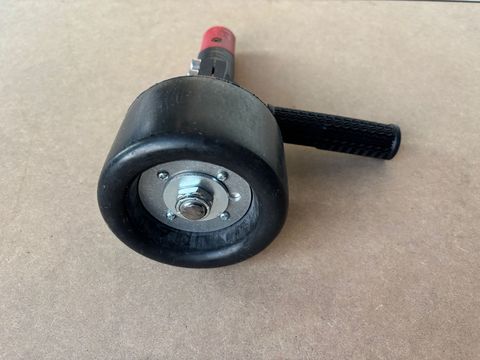 Black hand seam roller on a wooden surface.
