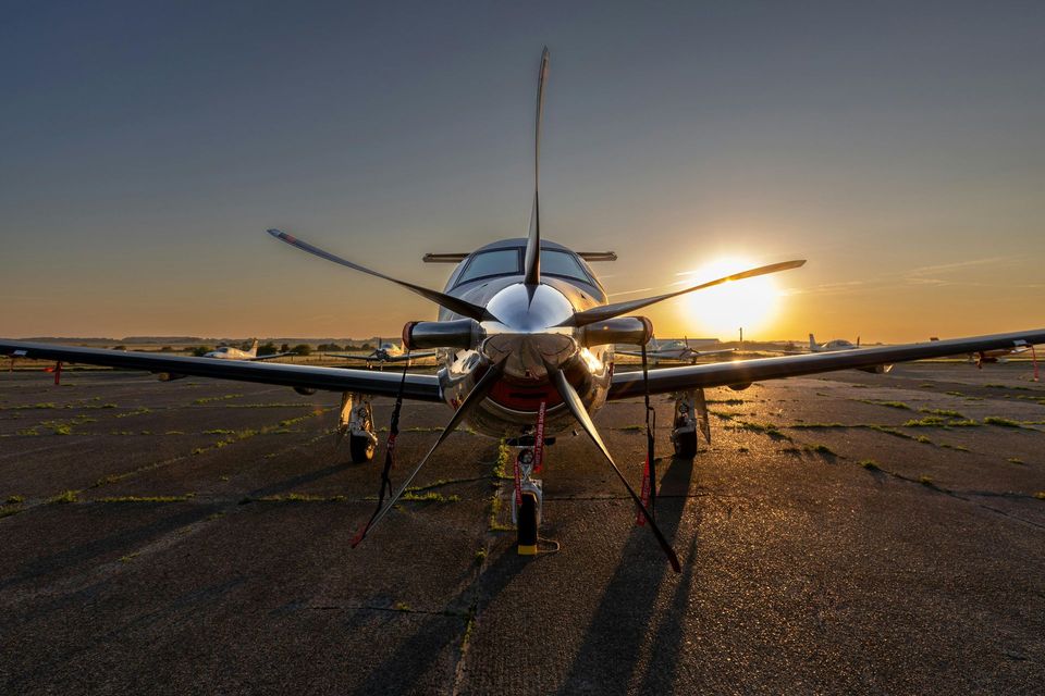 Turboprop airplane on runway at sunset; propeller blades blurred.