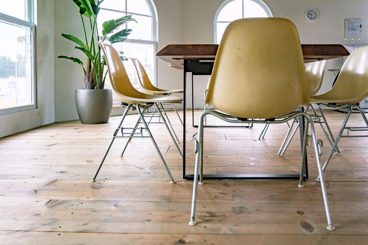 Bright dining room with yellow chairs, a wooden table, and large windows over a light wood floor