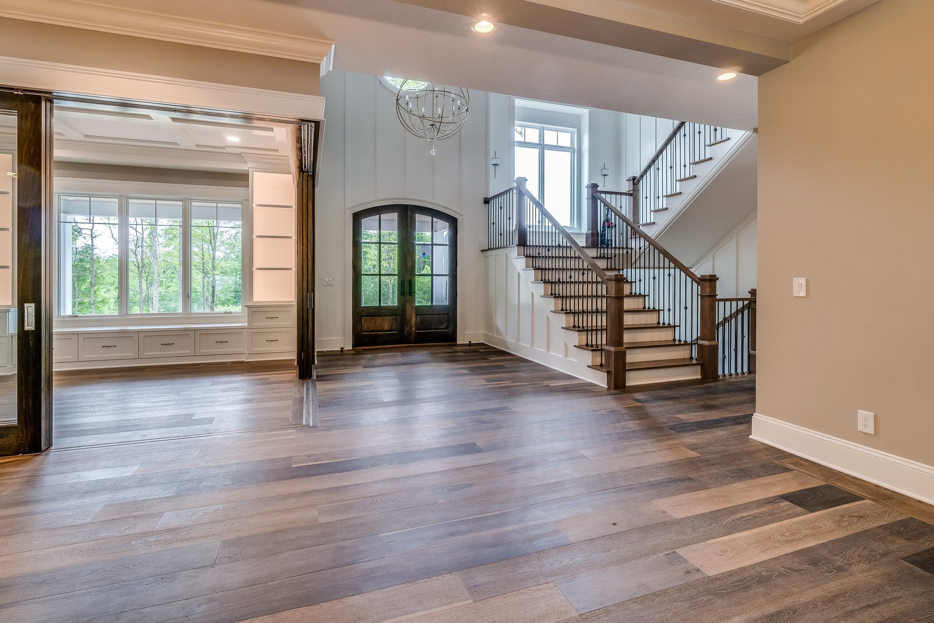 Spacious living room with hardwood floors, arched doorway, and staircase leading to an upper level