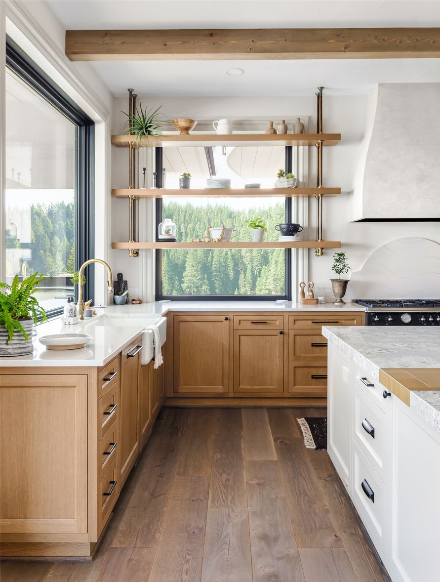 Bright modern kitchen with wooden cabinets, open shelves, white island, and large window.