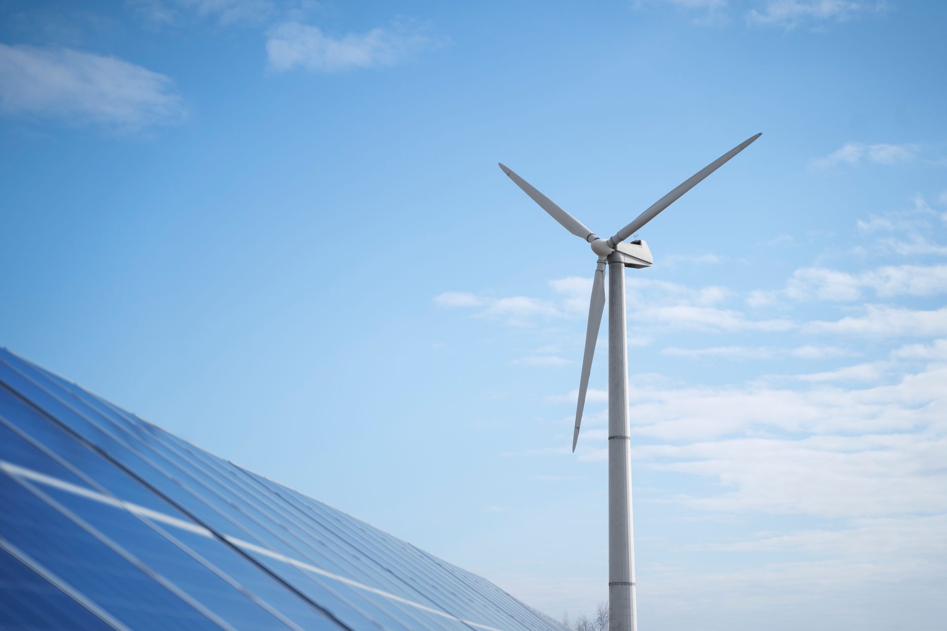 Une éolienne est assise à côté d'un panneau solaire.